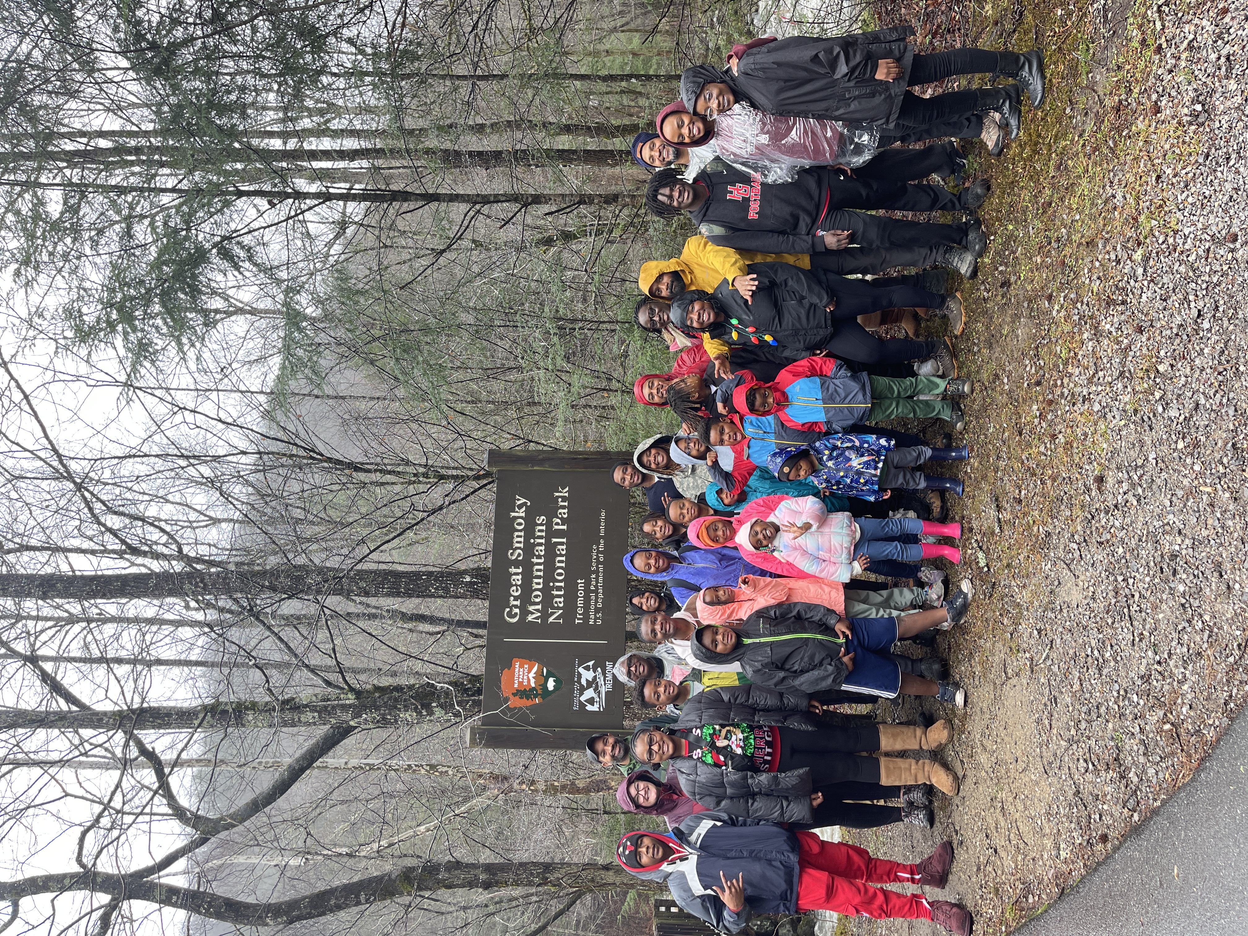 A large group of many ages stands in front of a Smoky Mountains sign